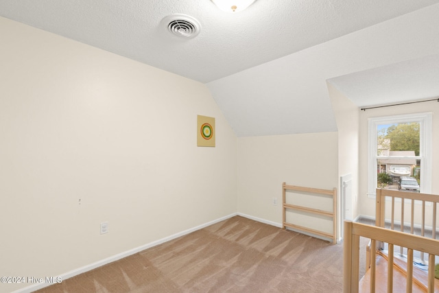 bonus room with a textured ceiling, light carpet, and vaulted ceiling