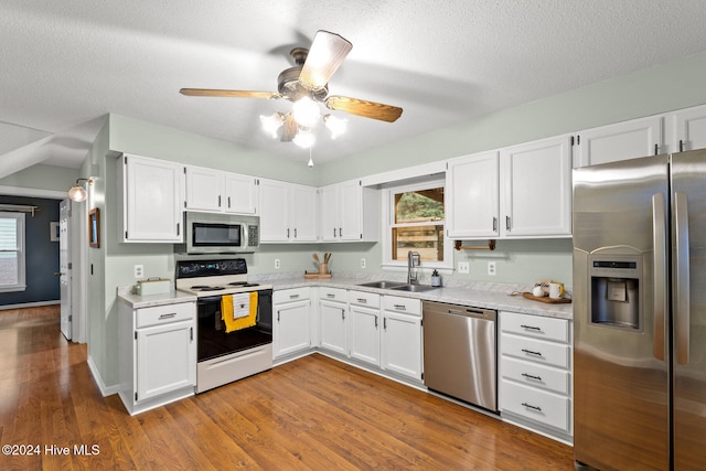 kitchen with sink, appliances with stainless steel finishes, hardwood / wood-style floors, and white cabinets