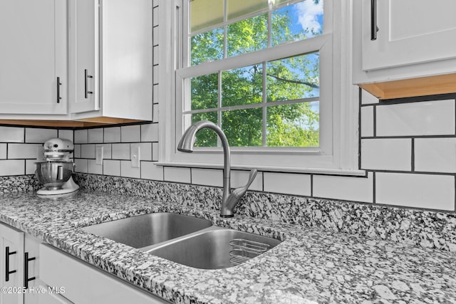 212 Outrigger Rd, New Bern, NC 28562 - kitchen view of a sink, white cabinetry, backsplash, and light stone countertops