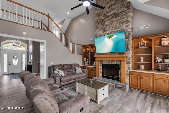 living room featuring high vaulted ceiling, light wood-type flooring, ceiling fan, and a fireplace