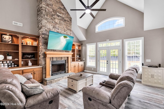 living room with a wealth of natural light, light hardwood / wood-style floors, a fireplace, and high vaulted ceiling