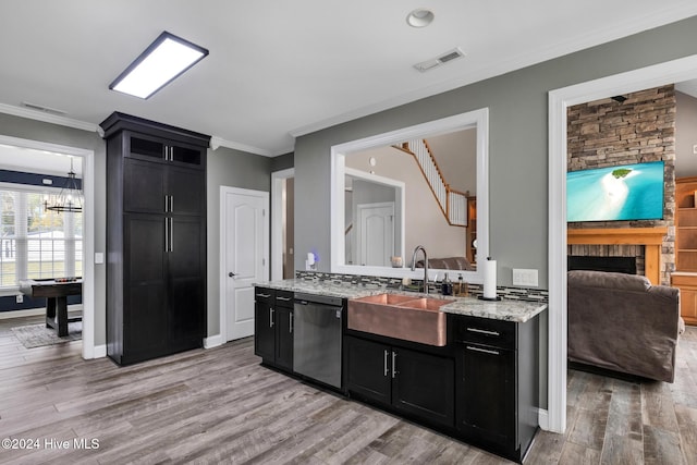 kitchen with sink, a stone fireplace, crown molding, light wood-type flooring, and dishwasher