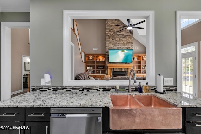 kitchen featuring a stone fireplace, backsplash, sink, stainless steel dishwasher, and ceiling fan