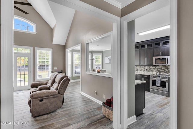 living room with hardwood / wood-style floors, ceiling fan, high vaulted ceiling, and crown molding