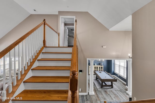 stairway with hardwood / wood-style floors, billiards, vaulted ceiling, and an inviting chandelier