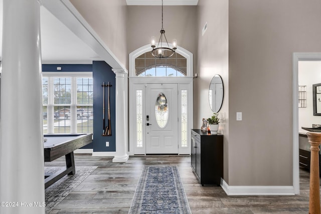 foyer featuring pool table, dark hardwood / wood-style flooring, a towering ceiling, decorative columns, and ornamental molding