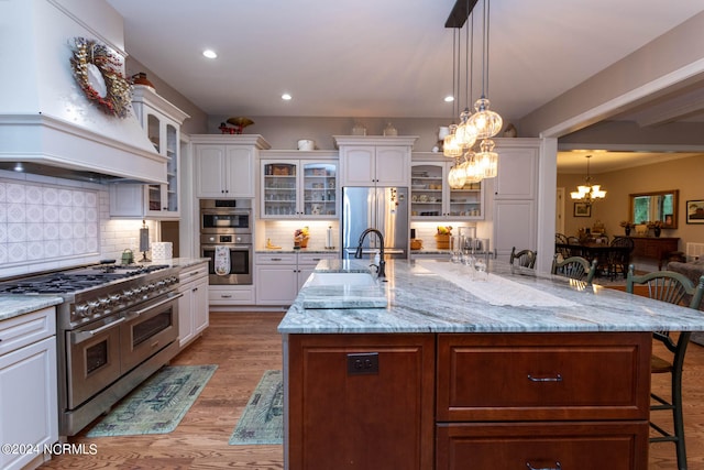 kitchen featuring a kitchen breakfast bar, custom range hood, a large island, white cabinetry, and stainless steel appliances