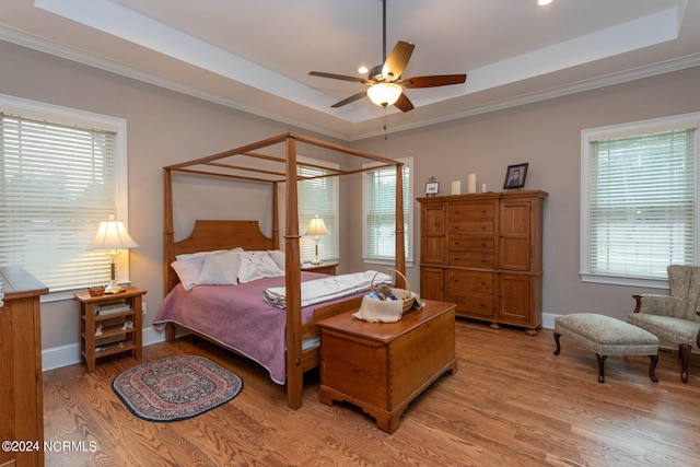 bedroom featuring a raised ceiling, ceiling fan, light hardwood / wood-style floors, and ornamental molding