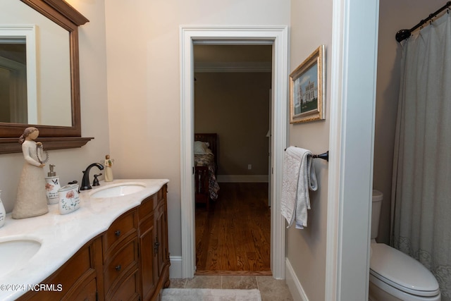 bathroom with ornamental molding, vanity, wood-type flooring, and toilet