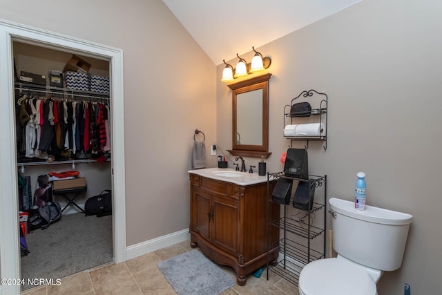 bathroom with tile patterned flooring, vanity, vaulted ceiling, and toilet