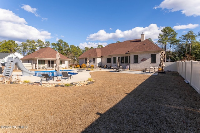 rear view of house featuring a yard, a fenced in pool, and a patio area