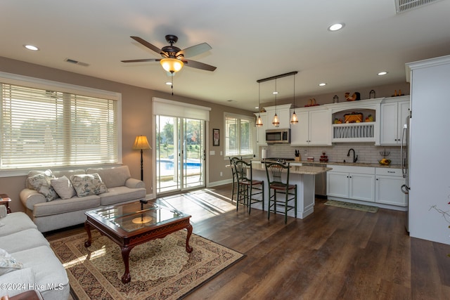 living room featuring dark hardwood / wood-style flooring, ceiling fan, and sink