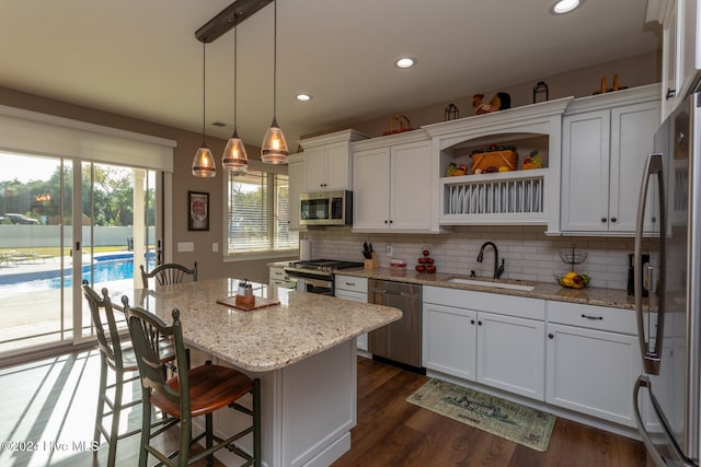 kitchen with a kitchen island, white cabinetry, sink, and appliances with stainless steel finishes