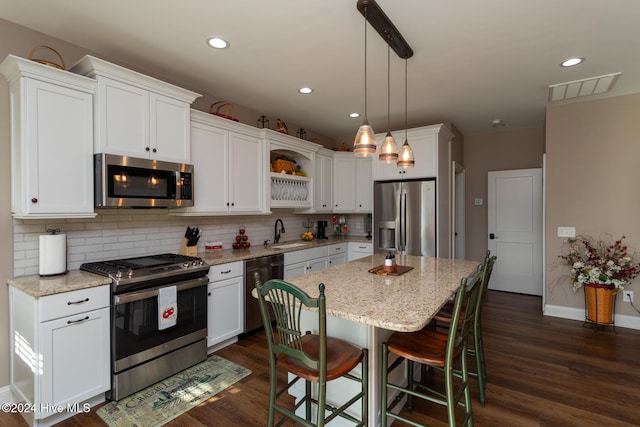 kitchen featuring appliances with stainless steel finishes, light stone counters, decorative light fixtures, white cabinets, and dark hardwood / wood-style floors