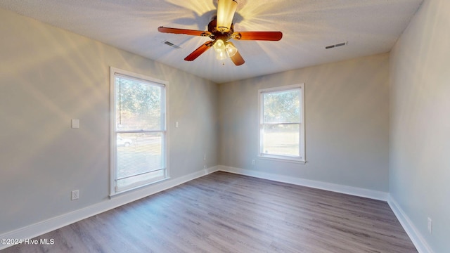 unfurnished room with hardwood / wood-style flooring, ceiling fan, a textured ceiling, and a wealth of natural light