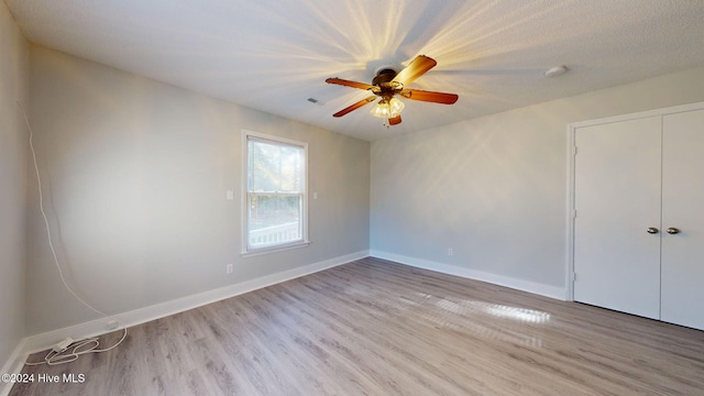 unfurnished bedroom featuring a closet, ceiling fan, and light hardwood / wood-style flooring