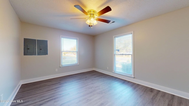 empty room featuring a textured ceiling, ceiling fan, dark wood-type flooring, and electric panel