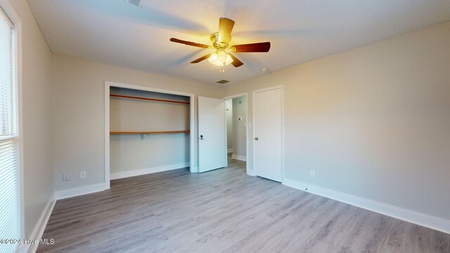 unfurnished bedroom with ceiling fan, light hardwood / wood-style floors, and a closet