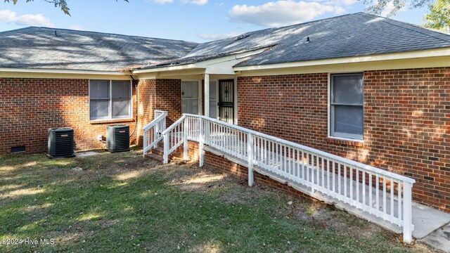 back of property featuring central AC unit and a lawn