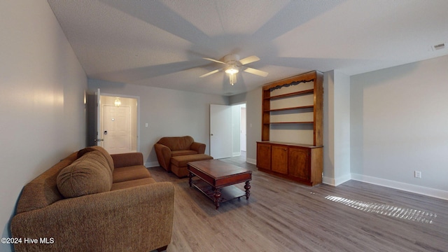 living room featuring ceiling fan, a textured ceiling, and light hardwood / wood-style flooring