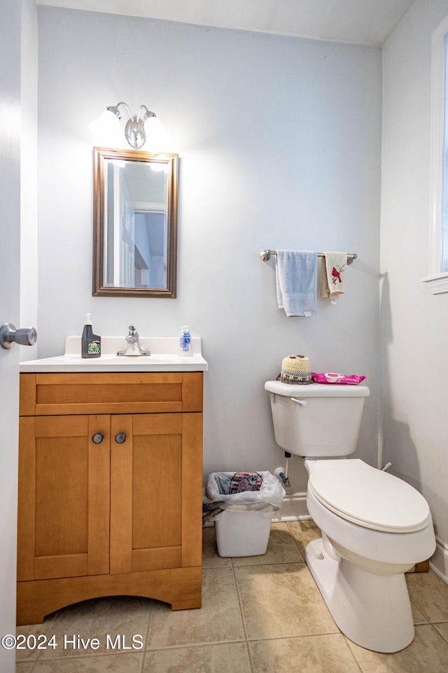 bathroom with toilet, vanity, and tile patterned floors