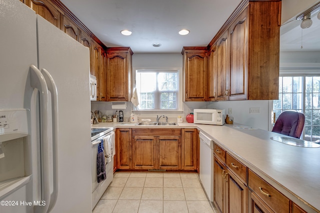 kitchen featuring light tile patterned floors, white appliances, and sink