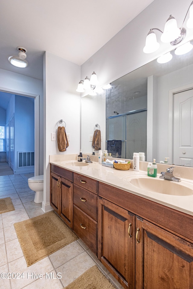 bathroom featuring toilet, vanity, tile patterned floors, and a shower with shower door