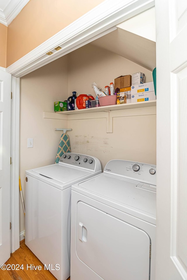 laundry room featuring hardwood / wood-style floors, separate washer and dryer, and ornamental molding