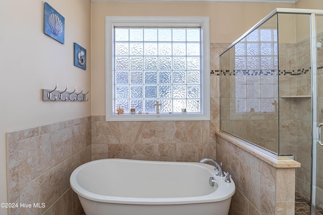 bathroom featuring tile walls and independent shower and bath