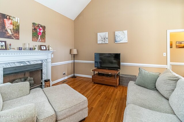 living room featuring a premium fireplace, wood-type flooring, and vaulted ceiling