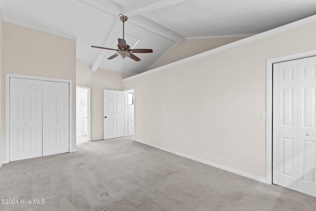 unfurnished bedroom with multiple closets, ceiling fan, beamed ceiling, and light colored carpet