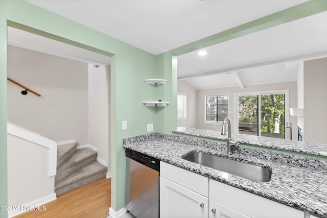 kitchen with light stone countertops, stainless steel dishwasher, sink, light hardwood / wood-style flooring, and white cabinets