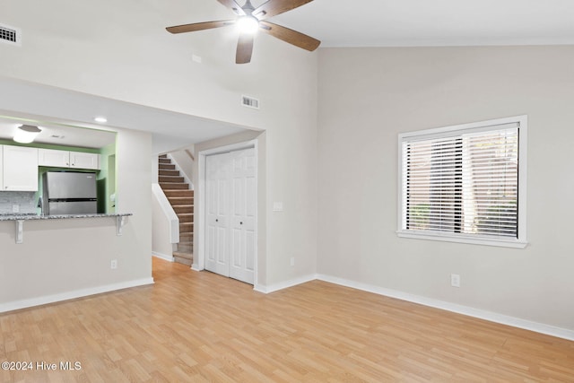 unfurnished living room featuring ceiling fan, high vaulted ceiling, and light wood-type flooring