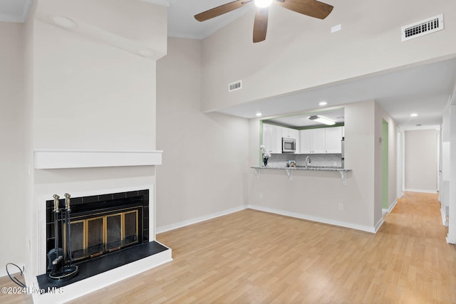 unfurnished living room with light hardwood / wood-style floors, ceiling fan, and ornamental molding