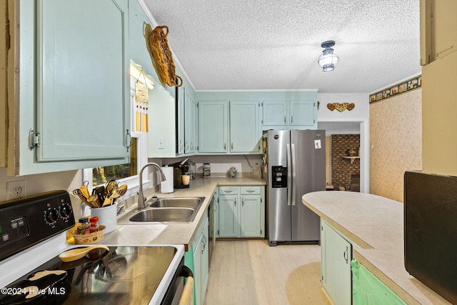 kitchen featuring sink, stainless steel refrigerator with ice dispenser, a textured ceiling, range, and light hardwood / wood-style flooring