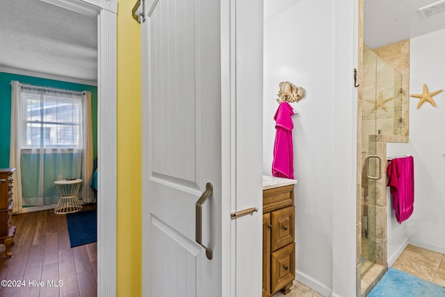 bathroom featuring a textured ceiling, vanity, hardwood / wood-style flooring, and a shower with shower door