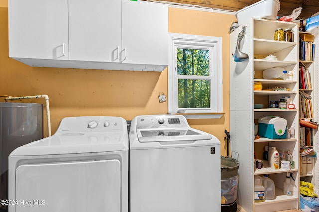 washroom with water heater, washing machine and dryer, and cabinets