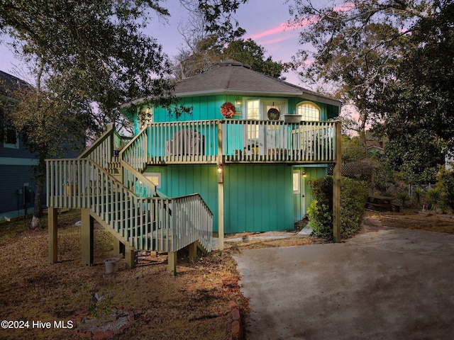 back house at dusk featuring a wooden deck