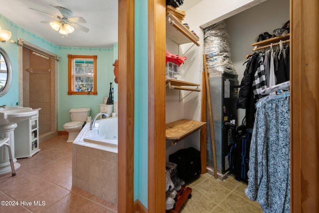 bathroom with tile patterned floors, toilet, ceiling fan, and tiled tub