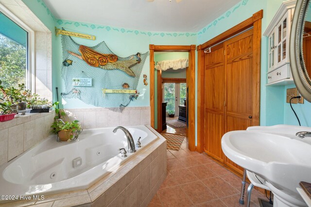 bathroom featuring tiled bath, tile patterned flooring, and sink