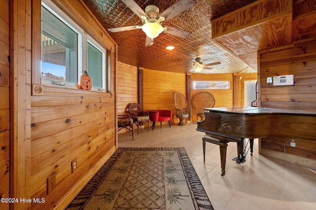 misc room with light tile patterned floors, ceiling fan, lofted ceiling, and wood walls