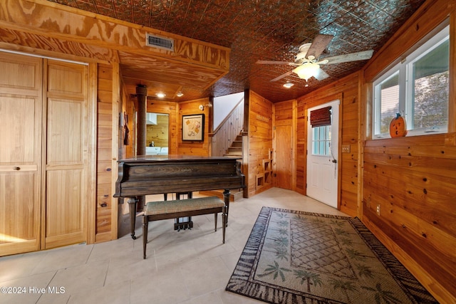 misc room featuring ceiling fan, wood walls, and light tile patterned floors