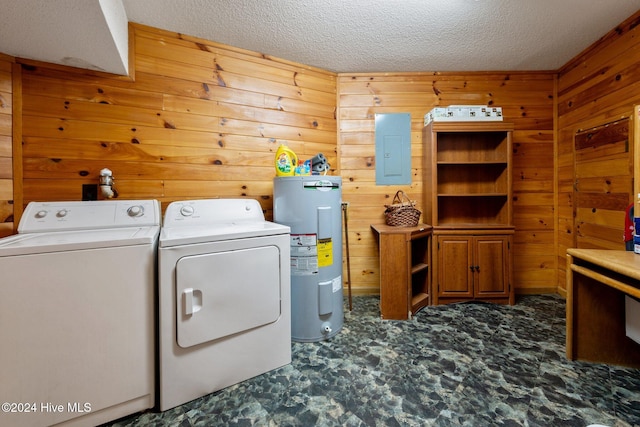 laundry room with washing machine and dryer, electric water heater, electric panel, wood walls, and a textured ceiling