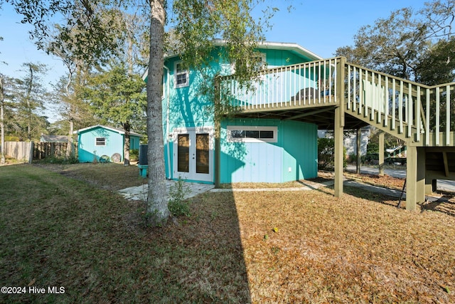 rear view of property with a lawn, a wooden deck, and a shed