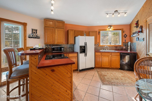 kitchen featuring black appliances, a healthy amount of sunlight, kitchen peninsula, and sink