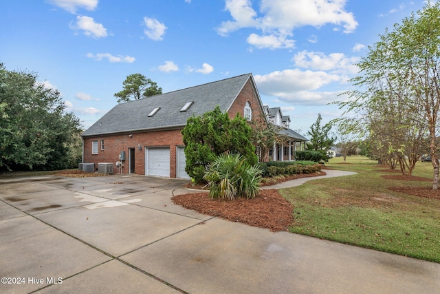 view of side of property with a yard, a garage, and central AC unit