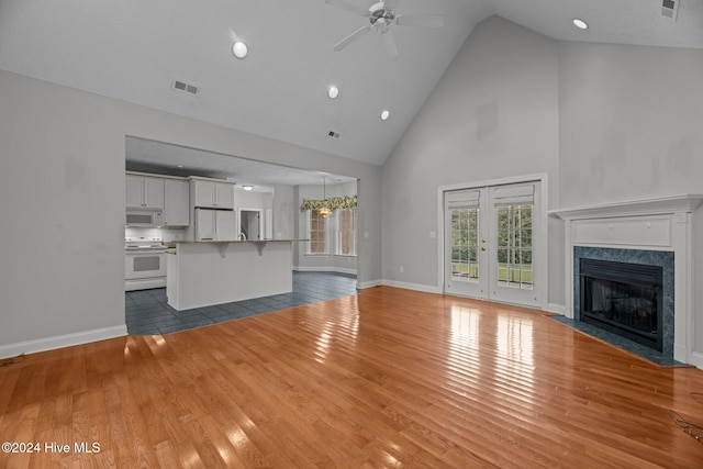 unfurnished living room with a textured ceiling, ceiling fan, high vaulted ceiling, a premium fireplace, and hardwood / wood-style floors