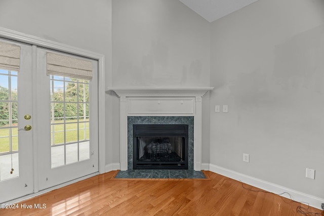 unfurnished living room with wood-type flooring and a tiled fireplace