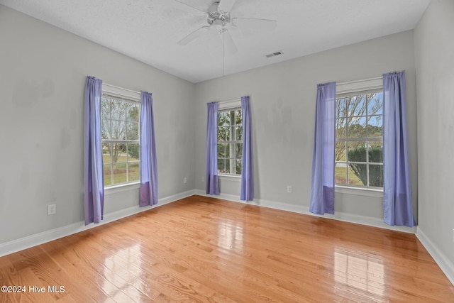 empty room featuring ceiling fan, hardwood / wood-style floors, and a healthy amount of sunlight