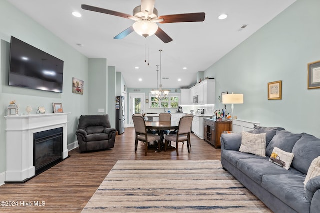 living room with ceiling fan with notable chandelier and dark hardwood / wood-style floors